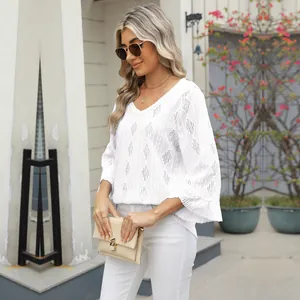 Detail view of a white hollow-out lace top with flare sleeves worn by a model outdoors
