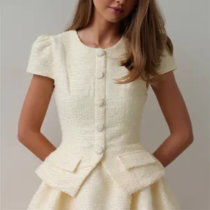 Detailansicht eines cremefarbenen Tweed-Zweiteilers mit einer eleganten Peplum-Jacke