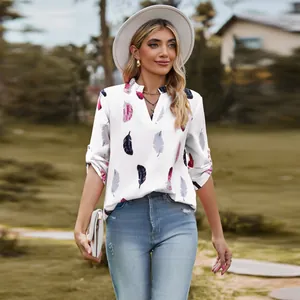 Woman wearing a stylish V-neck feather print blouse with three-quarter sleeves outdoors.