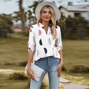 Outdoor lifestyle shot of a woman in a white V-neck feather print loose shirt