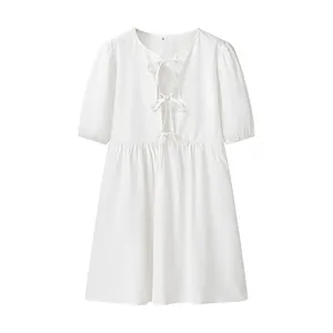 Détail d'une robe blanche à manches courtes avec liens à nouer sur le devant.
