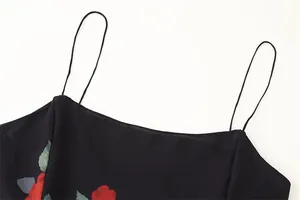 Close-up detail of the thin spaghetti straps and elegant red rose floral print on a black chiffon dress
