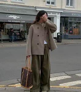 Mannequin de style urbain portant un caban court en laine beige avec un pantalon large olive.