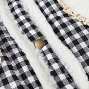 Close-up of black and white plaid jacket with white faux fur lining and bronze button detail