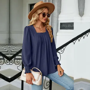 Detail showing the jacquard texture and pleated square neck design of the blue blouse.