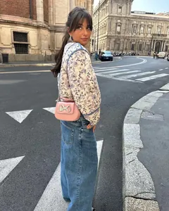 Model in een gewatteerd vest met bloemenprint in een chique stedelijke straat
