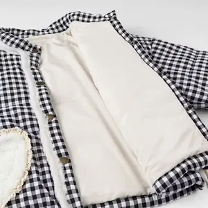 Detailed view showing the quilted cream lining and snap buttons of this gingham coat