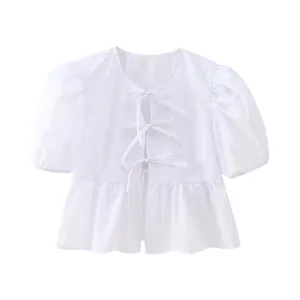 Vue détaillée d'une blouse blanche à manches bouffantes et nœuds élégants devant.