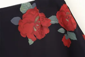 Close-up macro view of vibrant red rose floral print on high-quality black chiffon fabric texture