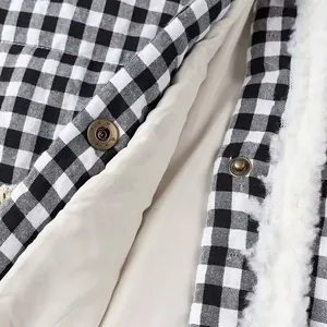 Detailed view of women's black and white plaid padded coat with brass buttons and white fur trim