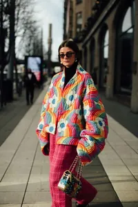 Ganzkörperaufnahme einer modischen Frau in einer bunten Steppjacke mit Blumenmuster im Freien