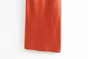 Gros plan sur l'ourlet lisse d'une robe midi en satin orange montrant la texture soyeuse du tissu