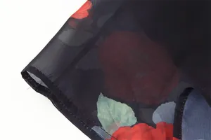 Close-up of sheer black fabric with vibrant red rose floral print and fine hem detailing