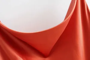 Gros plan détaillé du col bénitier élégant sur une robe nuisette en satin orange vif.
