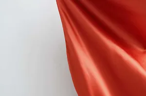 Détail de la texture du tissu en satin rouge sur une robe nuisette à col bénitier sexy