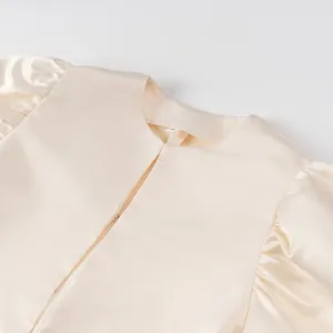 Close-up detail of cream satin top featuring elegant puff sleeves and round neckline