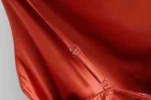 Gros plan sur la bretelle ajustable d'une élégante robe nuisette en satin roux