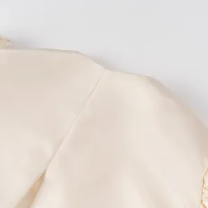 Detailed view of the smooth cream satin fabric and stitched seam on this puff sleeve top