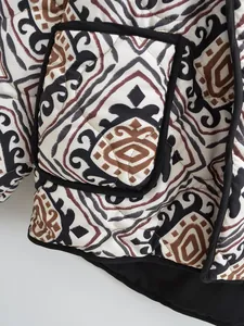 Close-up detail of a quilted jacket featuring an ethnic geometric print and black piping trim