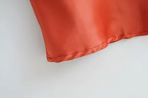 Gros plan sur l'ourlet d'une robe en satin orange montrant la finesse des coutures