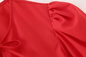 Détail macro d'un chemisier rouge à manches bouffantes avec nœud élégant au col.