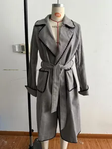 Vue détaillée d'un manteau en laine gris avec ceinture et bordures festonnées noires
