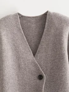 Close-up of grey knitted blazer texture featuring deep V-neck and single button detail