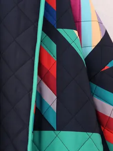 Close-up detail of geometric patchwork pattern and diamond quilting on women's cotton coat
