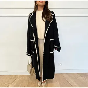 Détail d'un manteau en laine noir pour femme avec une bordure festonnée blanche élégante