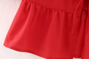Gros plan d'une chemise rouge avec ourlet à volants et cordon de serrage délicat.