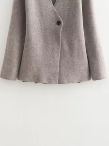 Close-up of elegant taupe knit blazer jacket showing soft fabric texture and button.