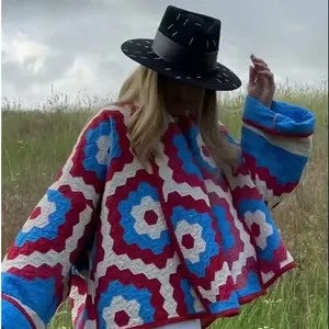 Street fashion woman wearing a geometric quilted kimono jacket in an outdoor field
