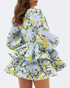 Back view of a light blue dress with yellow floral and bird print and ruffles