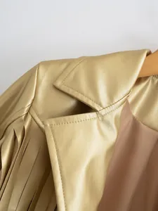 Close-up of gold metallic faux leather jacket with fringe detail and fine stitching.