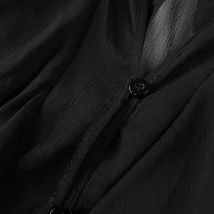 Macro detail of black V-neck shirt showing textured fabric and single-breasted button.