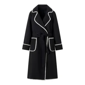 Vue détaillée d'un manteau en laine noir avec surpiqûres blanches et ceinture à nouer.