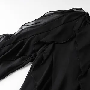 Close-up detail of layered ruffles on a black chiffon long-sleeve shirt fabric texture