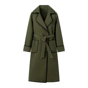Détail de manteau en laine vert avec bordure festonnée noire et ceinture