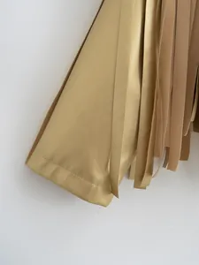 Close-up detail of a metallic gold leather jacket with stylish fringe and grain texture.