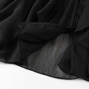 Detailed macro view of black sheer fabric with ruffle hem and button detail