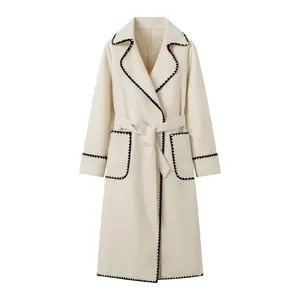 Détail d'un manteau en laine crème avec coutures à bords festonnés noirs