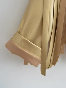 Detail view of gold metallic leather jacket with long fringe tassels and cuff detail.