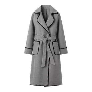 Détail d'un manteau en laine gris pour femme avec revers et garniture festonnée noire