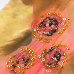 Detalle de bordado floral hecho a mano con cuentas y lentejuelas en vestido elegante