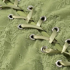 Macro detail of green floral lace corset with satin ribbon lace-up and metal eyelets