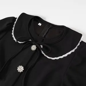 Close-up of detachable doll collar with lace trim and rhinestone flower buttons on black dress