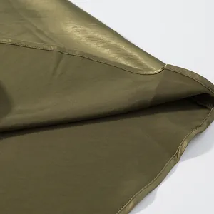 Close-up of olive green satin skirt hem showing fine stitching and smooth fabric texture.