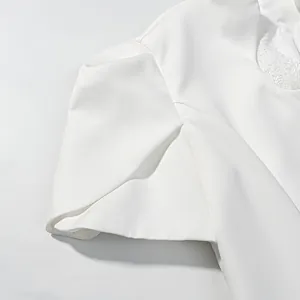 Detail view of white short-sleeve top with lace neckline and structured slit sleeves.