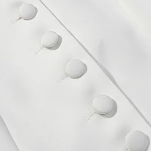 Close-up of white fabric-covered buttons on a tweed-style short sleeve top