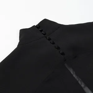 Detailopname van de knoopsluiting in de nek en het mesh-paneel van een zwarte jumpsuit